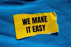 We make it easy message written on ripped torn yellow paper piece with blue background. Conceptual we make it easy symbol. Copy space. photo