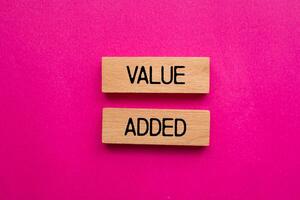 Value added message written on wooden blocks with pink background. Conceptual value added symbol. Copy space. photo