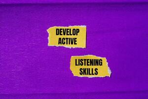 Develop active listening skills message written on ripped torn yellow paper pieces with purple background. Conceptual develop active listening skills symbol. Copy space. photo