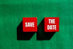 Save the date message written on red wooden cubes with green background. Conceptual save the date symbol. Copy space. photo
