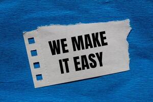 We make it easy message written on ripped torn paper piece with blue background. Conceptual we make it easy symbol. Copy space. photo