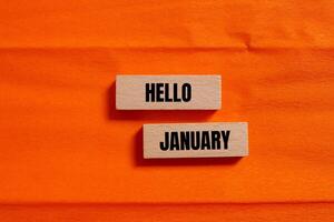 Hello january message written on wooden blocks with orange background. Conceptual hello january symbol. Copy space. photo