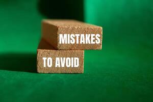 Mistakes to avoid message written on wooden blocks with green background. Conceptual mistakes to avoid symbol. Copy space. photo
