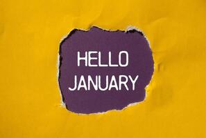 Hello january message written on ripped torn yellow paper with purple background. Conceptual hello january symbol. Copy space. photo