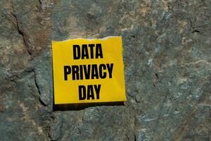 Data privacy day message written on ripped torn yellow paper piece with stone background. Conceptual data privacy day symbol. Copy space. photo