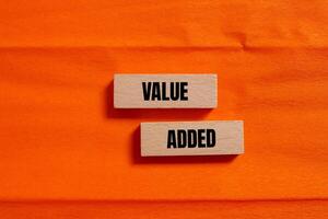 Value added message written on wooden blocks with orange background. Conceptual value added symbol. Copy space. photo