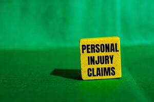 Personal injury claims message written on yellow wooden cube with green background. Conceptual personal injury claims symbol. Copy space. photo