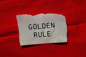 Golden rule message written on ripped torn paper piece on red background. Conceptual golden rule symbol. Copy space. photo