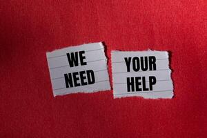 We need your help message written on ripped torn paper piece with red background. Conceptual we need your help symbol. Copy space. photo