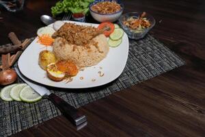 Delicious homemade roast chicken legs with fried onions served with spicy pulao close-up in a plate on the table. Horizontal photo