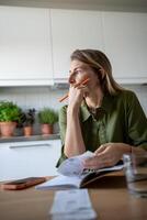 Thoughtful female analysing budget, verifying income and expenses, thinking while looking at window photo