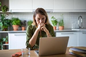 Focused thoughtful woman with laptop deep in process of solving tasks problems remote work IT field. photo