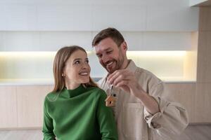 Glad smiling family hugging with keys to new apartment after moving in, celebrating new real estate photo