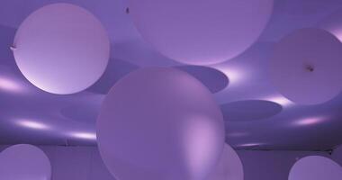 Light reflects off a violet ceiling adorned with colorful balloons, creating a vibrant and festive atmosphere indoors video
