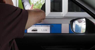 Driver making contactless payment with smartphone through open car window at highway toll station video
