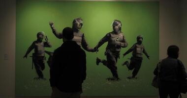 Amsterdam, Netherlands - 28 August, 2024. Visitors at Moco Museum viewing Banksy artwork of riot police in an open field video