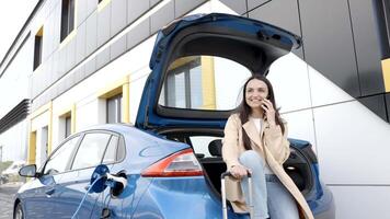 Young woman waiting charging automobile battery from small public station and using smartphone while charging automobile video