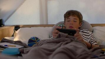 A teenage boy lying in bed inside a cozy glamping tent, using his phone. Soft blankets and personal items add a sense of comfort and relaxation to the setting video
