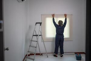 Worker Setting Up Window Blinds with Ladder and Toolbox in Minimalist Room photo
