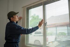 Worker Adjusting Window Blinds with Natural Light in Modern Interior photo