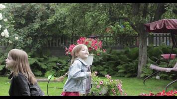 Children have fun in the rain. Two sisters are running around having fun in the rain in the yard at home. video