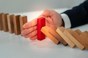 insurance with hands protect domino. Businessman hands stop dominoes falling in business crisis. business risk control and planning and strategies to run prevent insurance businesses. photo