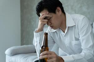 Depressed young business man addicted feeling bad drinking whiskey alone at home, stressed frustrated lonely drinking alcohol suffers from problematic liquor, alcoholism, life and family problems photo