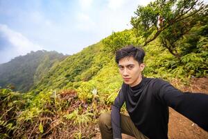 Man in the Wilderness, Posing Proudly on Mountain Peak. Serene Nature View from the Top of the Mountain. photo
