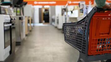 A man walks through an electronics hypermarket with shopping cart and chooses household appliances video