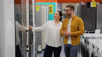 Just married couple open door of the refrigerator in the hardware electronics store and compare with other models video