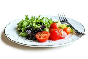 Fresh green salad with cherry tomatoes and black pepper on a white plate with a fork. photo