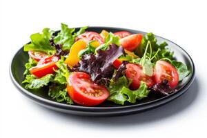 Fresh salad with tomatoes, lettuce, and avocado on a black plate. photo