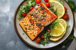 Close up of pan seared salmon with lemon and cherry tomatoes on a plate. photo