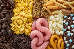 Assorted candy and snacks on a wooden surface photo