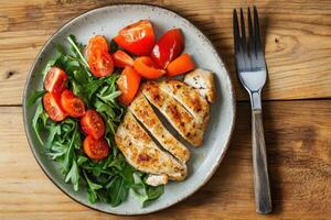 A plate with chicken, tomatoes and salad photo