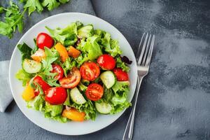 A plate of salad with tomatoes, cucumbers and lettuce photo