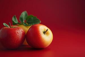 Three red and yellow apples with green leaves on a red background. photo