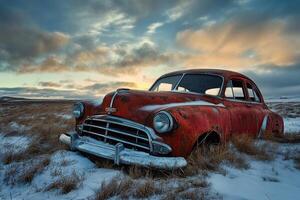 Rusty red vintage car in a snowy field at sunset. photo
