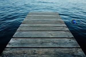 Wooden dock extending into calm blue water. photo