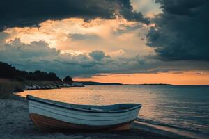 A small boat sits on a sandy beach at sunset with a dramatic sky above. photo
