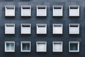 A symmetrical grid of windows on a gray building facade. photo