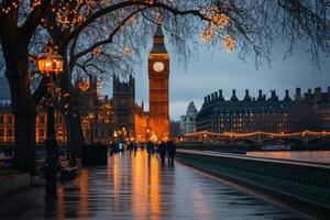 A view of Big Ben and the Houses of Parliament in London, England at dusk. The walkway is wet from rain and lit with string lights on the trees. photo