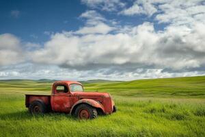 A vintage red pickup truck sits in a field of green grass under a blue sky with white clouds. photo
