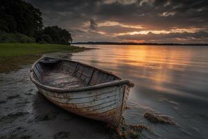 A weathered boat rests on the shore of a tranquil lake at sunset. photo