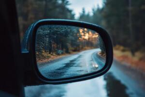 A winding road through a foggy forest reflected in a car's side mirror. photo