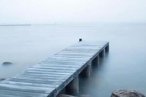 A wooden pier extends into a foggy lake. photo