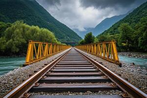 A yellow railway bridge over a river leads into the mountain. photo