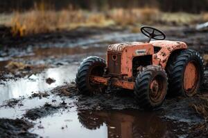 An old, rusty tractor sits in a muddy field. photo