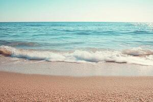 Gentle waves lap at the shore of a sandy beach. photo