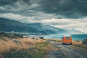 An orange van is parked on a road near the ocean photo